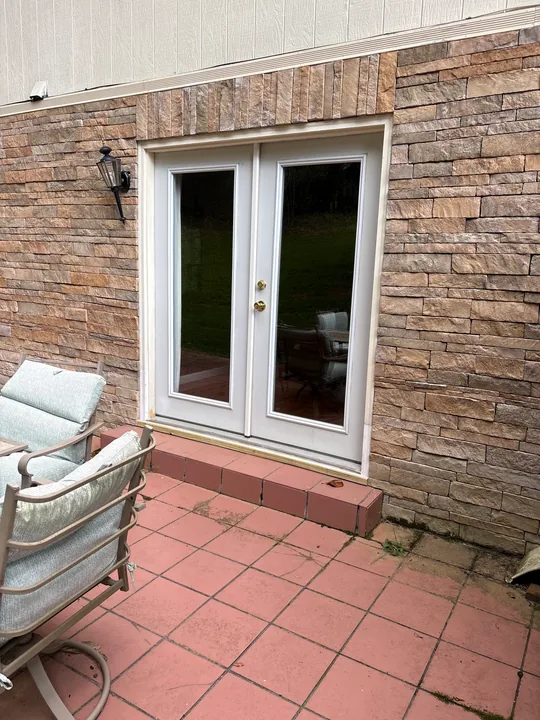 White double patio doors in a brick wall beside a tiled patio