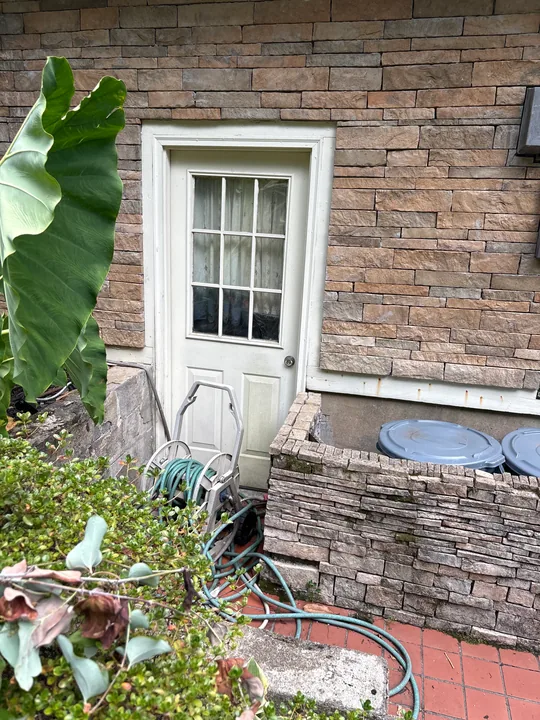 White double patio doors in a brick wall beside a tiled patio