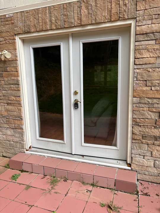 White double patio doors in a brick wall beside a tiled patio
