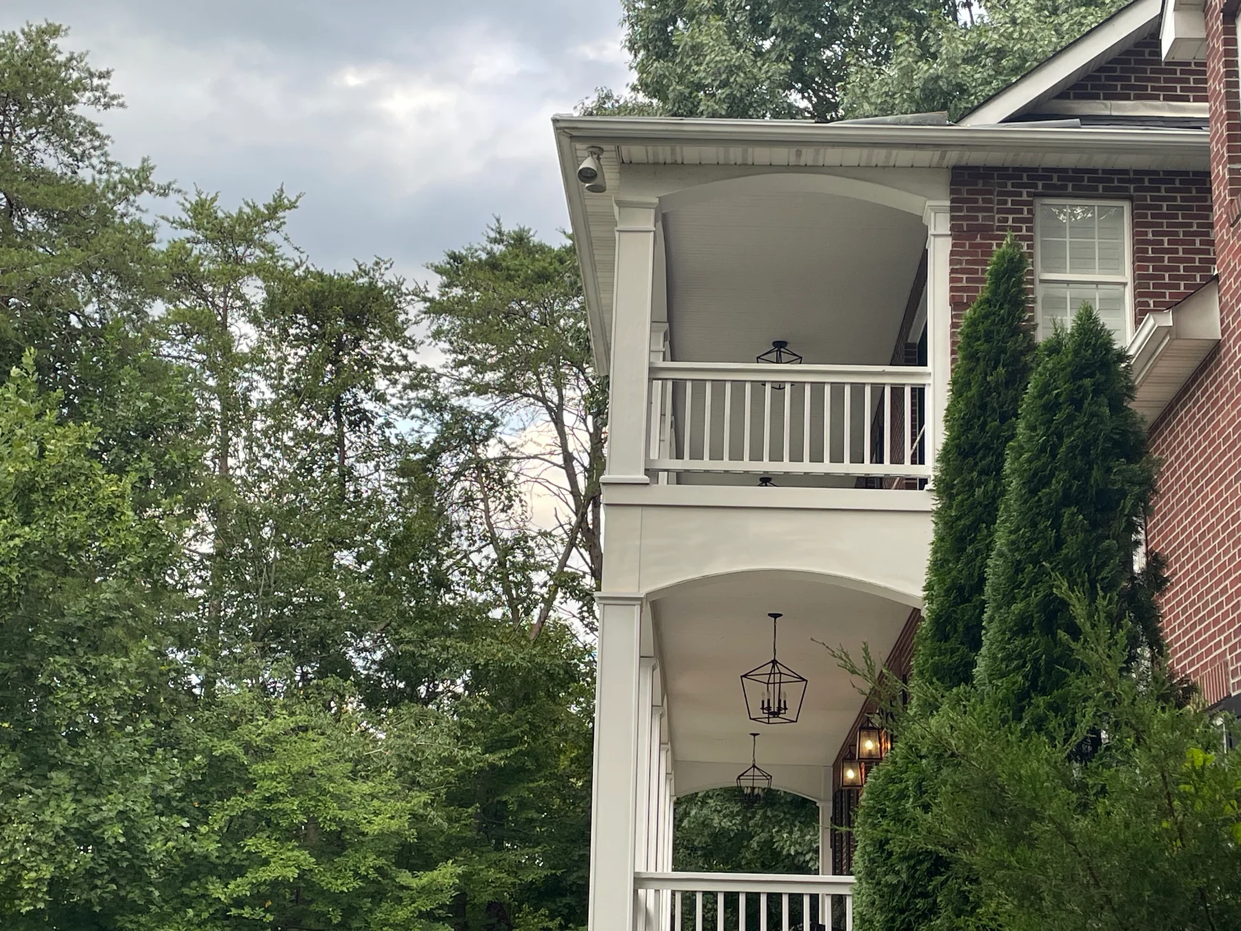 White porch columns and railings surrounded by leafy trees