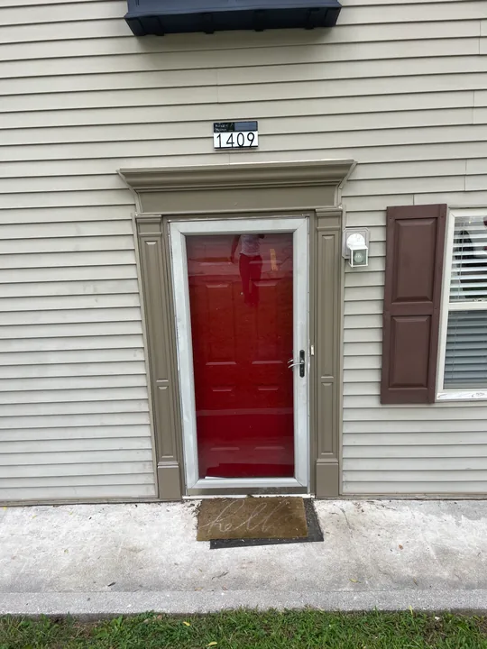 Red entry door with white casing and a light above the doorway
