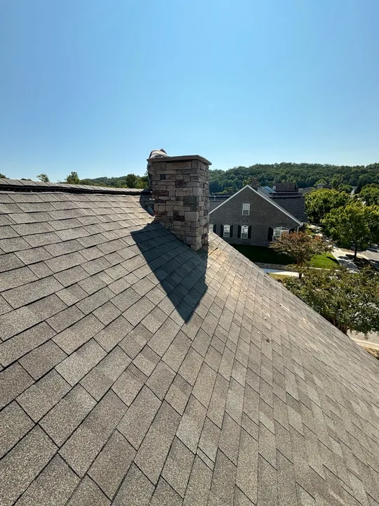 Shingled roof and chimney flashing under a blue sky