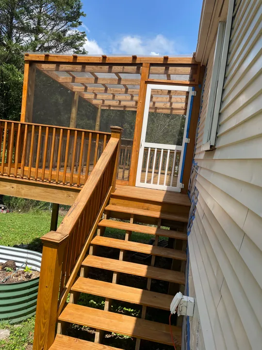 Timber steps, railing and screened porch beside a home