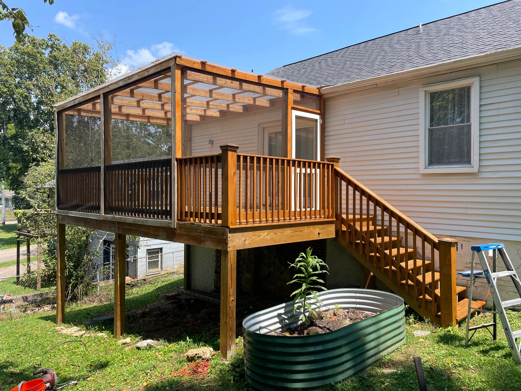Timber steps, railing and screened porch beside a home