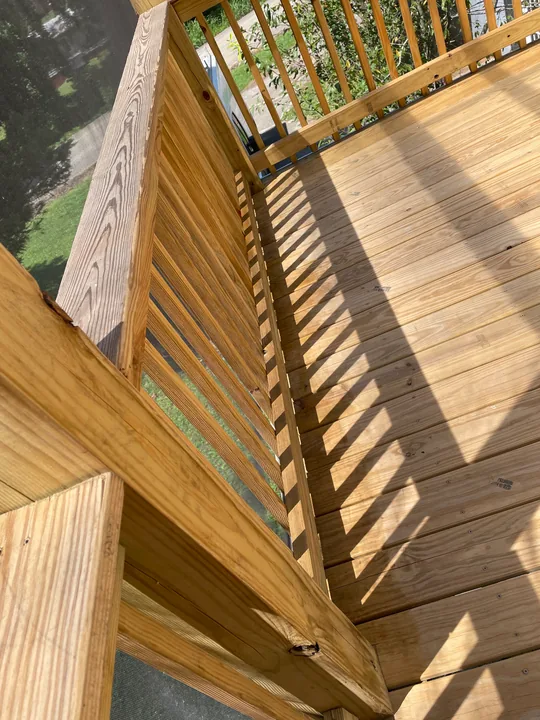 Timber steps, railing and screened porch beside a home