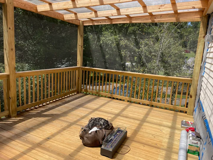 Timber steps, railing and screened porch beside a home