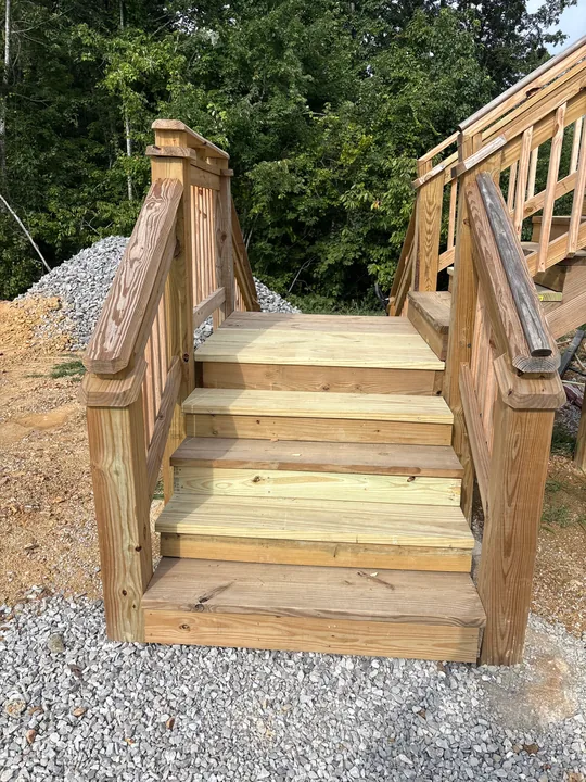Timber steps, railing and screened porch beside a home
