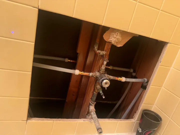 Open shower wall exposing the mixing valve and pipework
