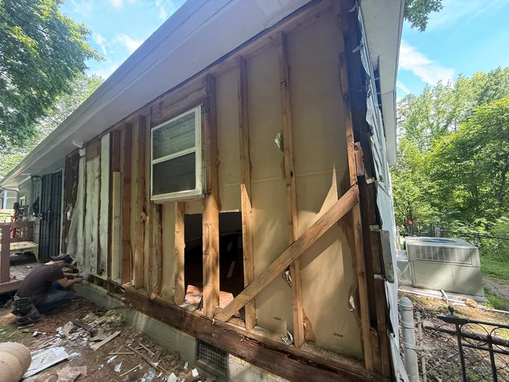 Exterior siding repair and wall framing beside a home
