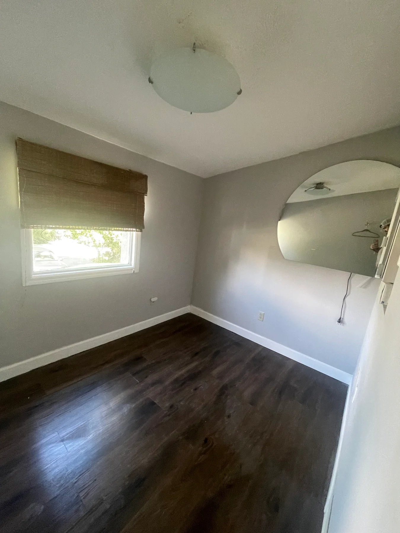 Remodeled sloped-ceiling room with painted walls, dark plank flooring and a window