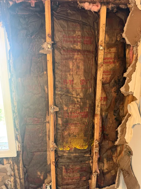 Wall opened beside the window during demolition of the same sloped-ceiling room