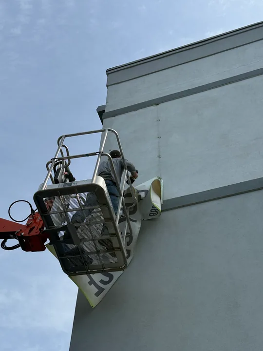 Crew using a boom lift for exterior banner placement