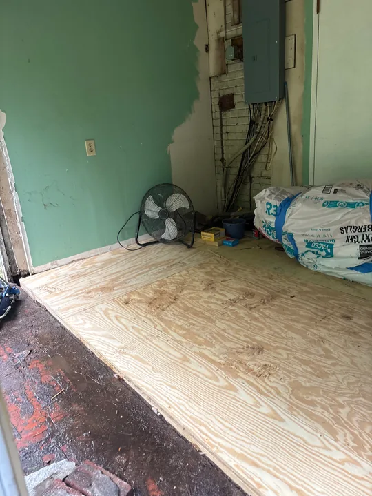 Exposed and replaced sheet subfloor beside room walls