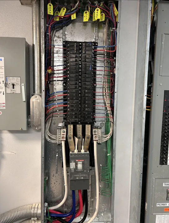 Open electrical panel showing breakers and circuit conductors