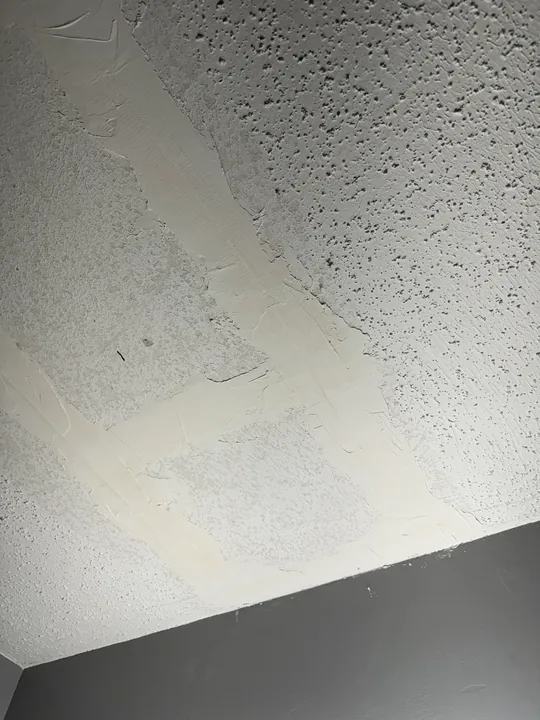 Textured ceiling surface and a fitted drywall patch around a fixture opening