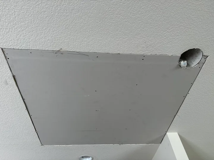 Textured ceiling surface and a fitted drywall patch around a fixture opening