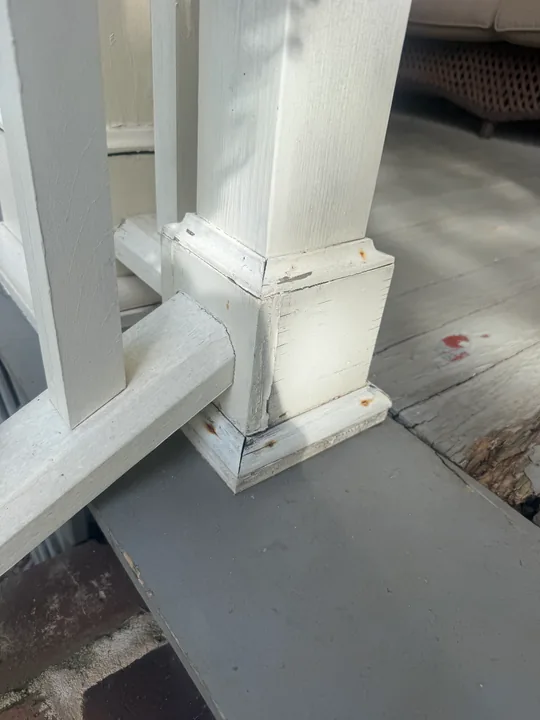 White porch column trim and exposed repair area at the base