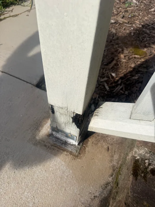 White porch column trim and exposed repair area at the base