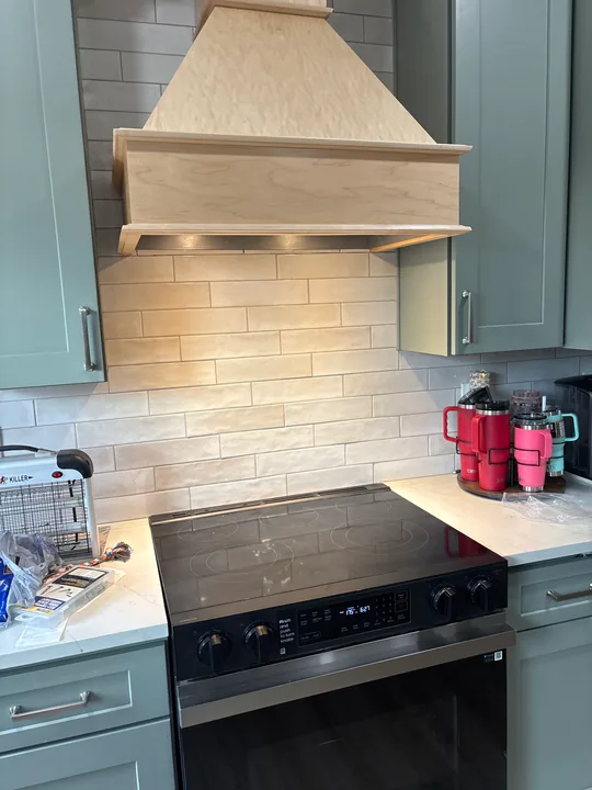 Wood range hood and cabinetry above a kitchen range