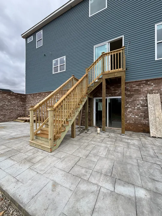 Timber exterior staircase, upper landing and railings beside a home