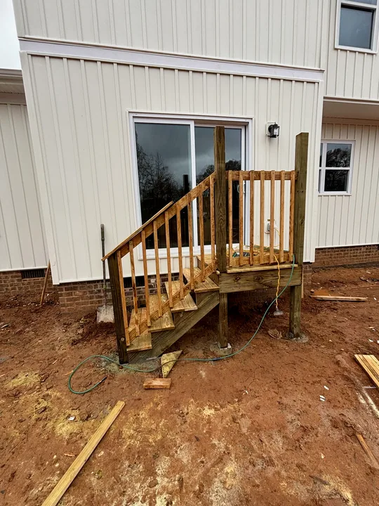 Timber exterior staircase, upper landing and railings beside a home