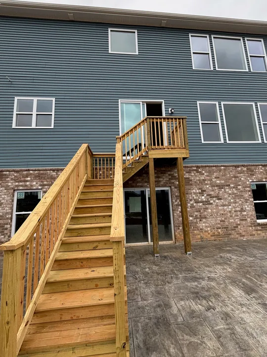 Timber exterior staircase, upper landing and railings beside a home