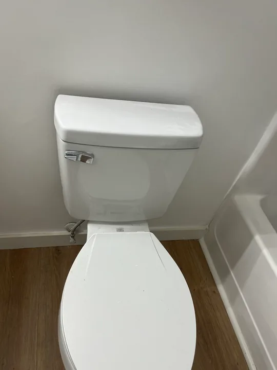White toilet beside a bathroom vanity and tub
