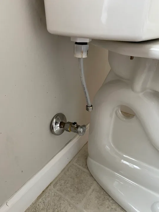 White toilet and its nearby shutoff connection
