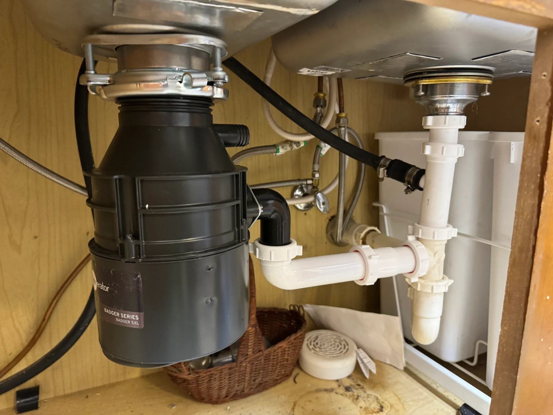 Kitchen sink drain, disposal and plumbing connections beneath a counter