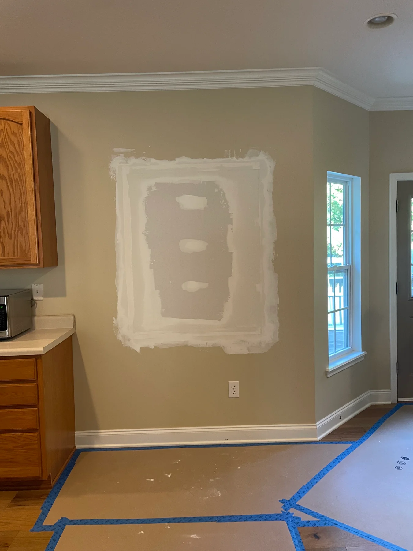 Drywall patch, joint compound and protected flooring in a room
