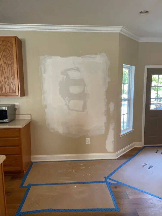 Drywall patch, joint compound and protected flooring in a room