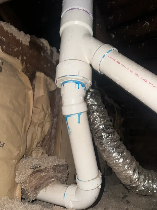 White waste pipes and connection fittings beneath a floor