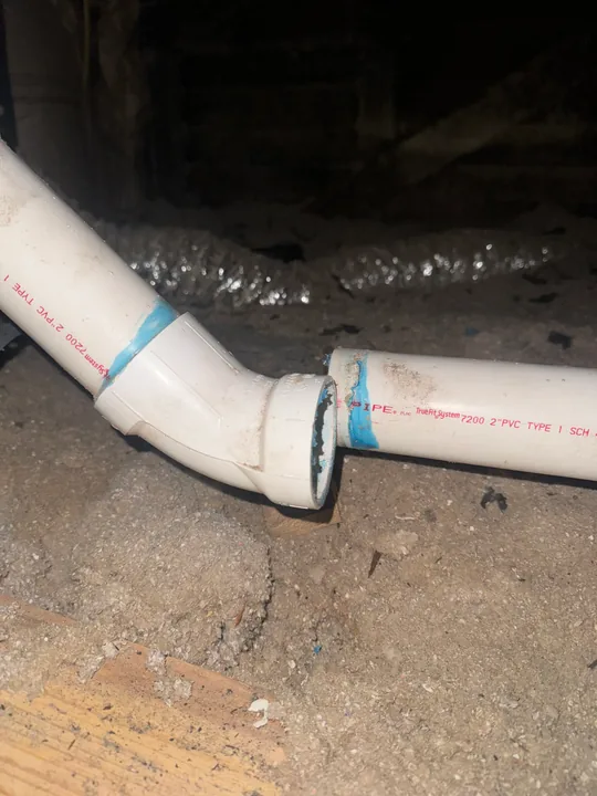 White waste pipes and connection fittings beneath a floor