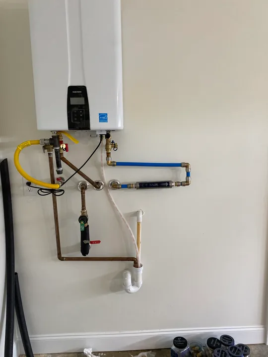 Wall-mounted tankless water heater and visible pipe connections