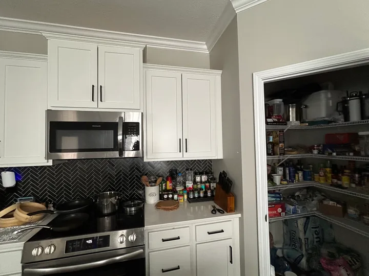 White kitchen cabinet doors with dark pulls and surrounding worktop