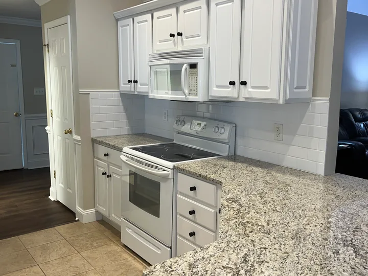White kitchen cabinetry, light countertops and appliances