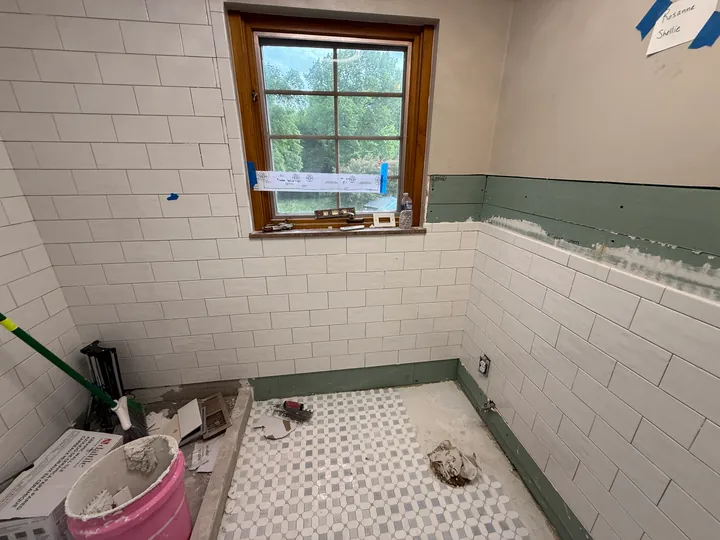 White wall tile and mosaic floor during the bathroom remodel, before fixtures are installed
