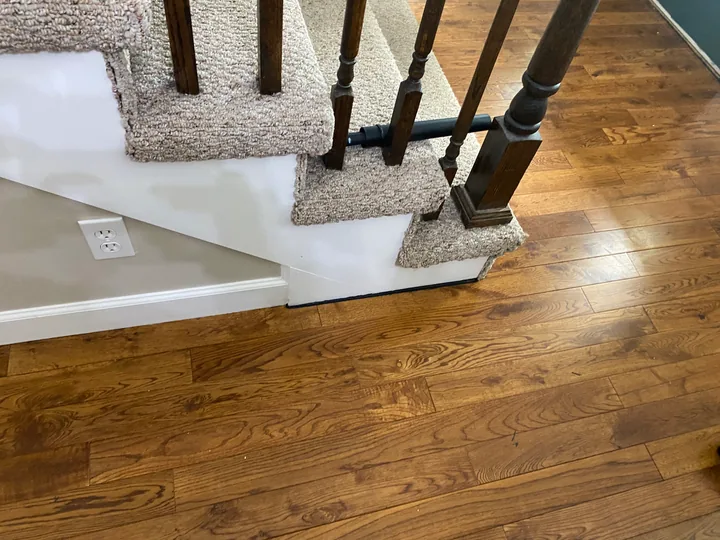 Wood-grain floor beside a staircase and white stair skirt